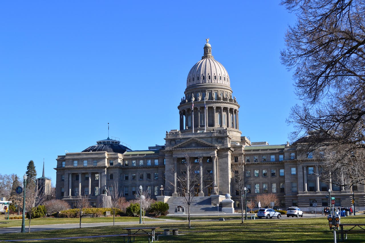 The Idaho State Capitol Building stands majestically under a clear blue sky with surrounding gardens.